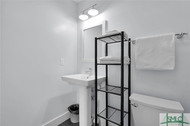 half bathroom with tile patterned flooring, toilet, and baseboards