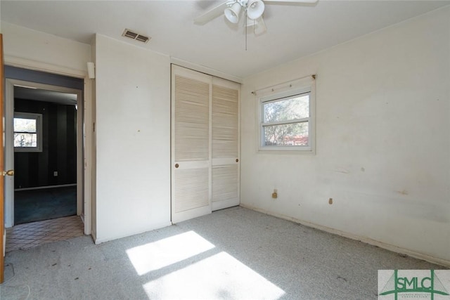 unfurnished bedroom featuring a closet, visible vents, multiple windows, and carpet flooring