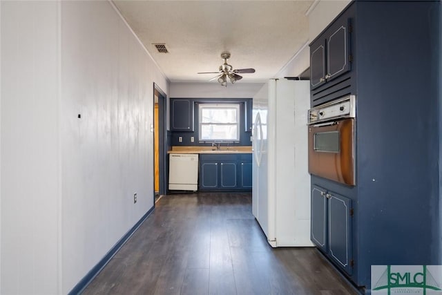 kitchen featuring white appliances, visible vents, dark wood finished floors, a sink, and ceiling fan