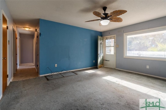 carpeted empty room with ceiling fan, a textured ceiling, and baseboards