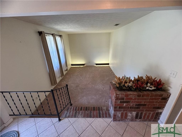 stairway featuring tile patterned floors, visible vents, carpet floors, and a textured ceiling