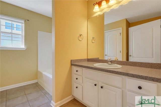 bathroom with tile patterned flooring, vanity, baseboards, and a bathtub