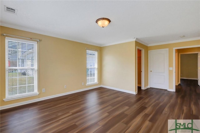 empty room featuring dark wood finished floors, visible vents, baseboards, and ornamental molding