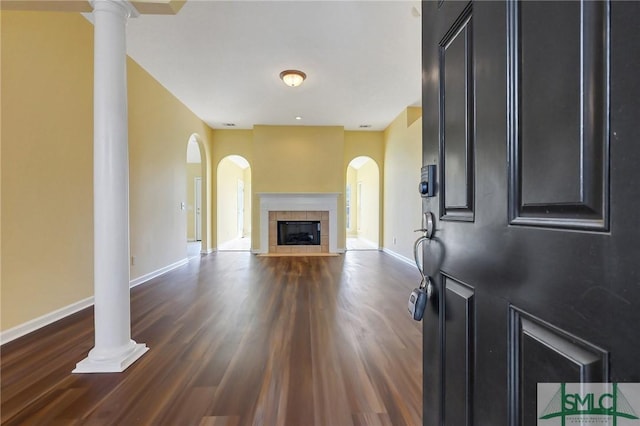 unfurnished living room with baseboards, arched walkways, and wood finished floors