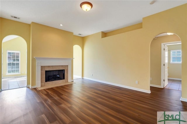 unfurnished living room with visible vents, plenty of natural light, and arched walkways