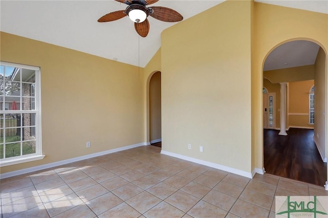 unfurnished room featuring vaulted ceiling, light tile patterned flooring, arched walkways, plenty of natural light, and a ceiling fan