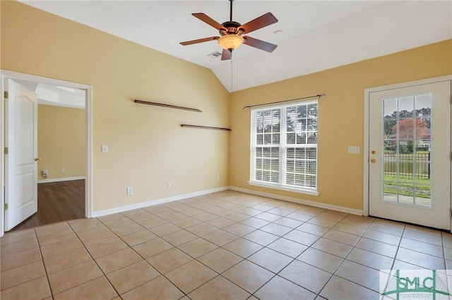 empty room featuring vaulted ceiling, light tile patterned floors, baseboards, and ceiling fan