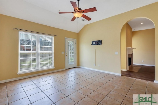 unfurnished room featuring light tile patterned floors, baseboards, a ceiling fan, and vaulted ceiling