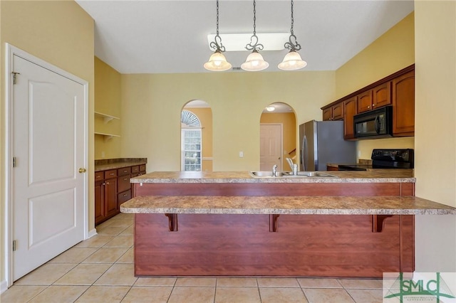 kitchen with a sink, a kitchen bar, arched walkways, and black appliances