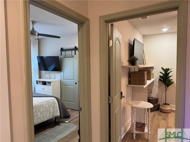 hallway with visible vents, a barn door, baseboards, and wood finished floors