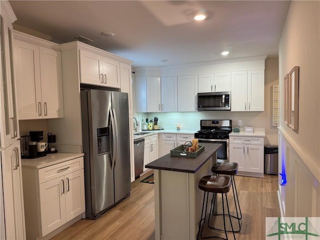 kitchen with white cabinetry, appliances with stainless steel finishes, a breakfast bar, and light wood-type flooring