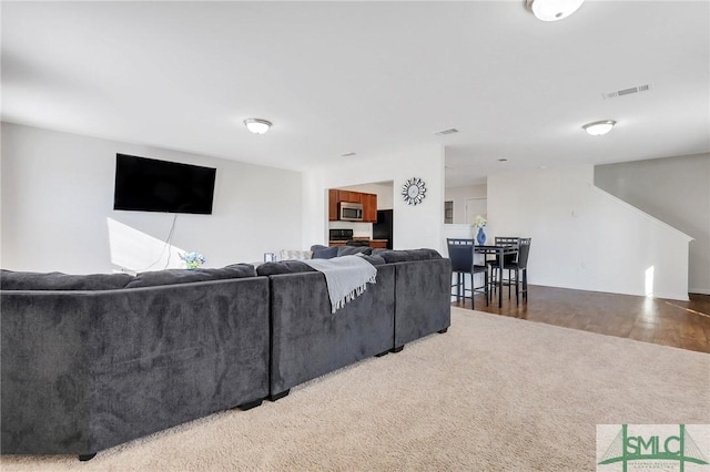 living area featuring visible vents and wood finished floors