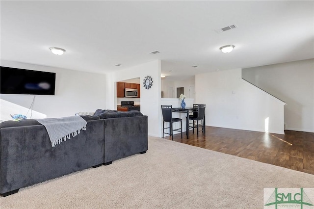 carpeted living room with visible vents and wood finished floors