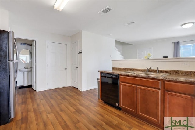 kitchen featuring visible vents, a sink, dark wood-style floors, freestanding refrigerator, and dishwasher