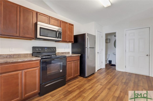 kitchen featuring appliances with stainless steel finishes, wood finished floors, and brown cabinetry