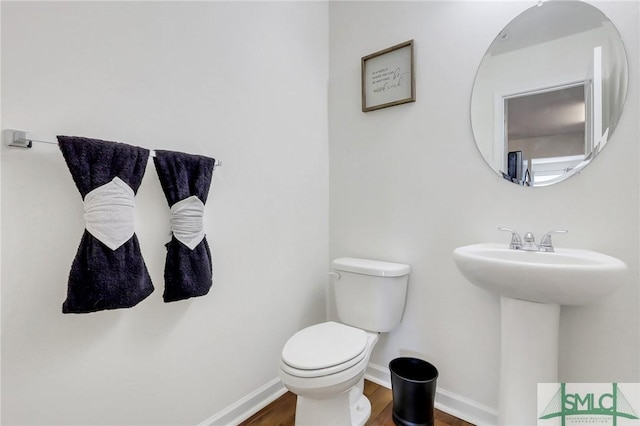 bathroom with toilet, wood finished floors, and baseboards