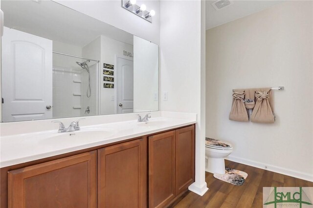 full bathroom featuring visible vents, toilet, double vanity, wood finished floors, and a shower