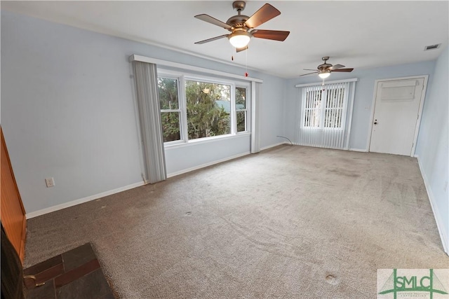 carpeted spare room featuring a ceiling fan, visible vents, and baseboards