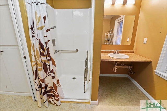 bathroom featuring a sink, baseboards, and a stall shower