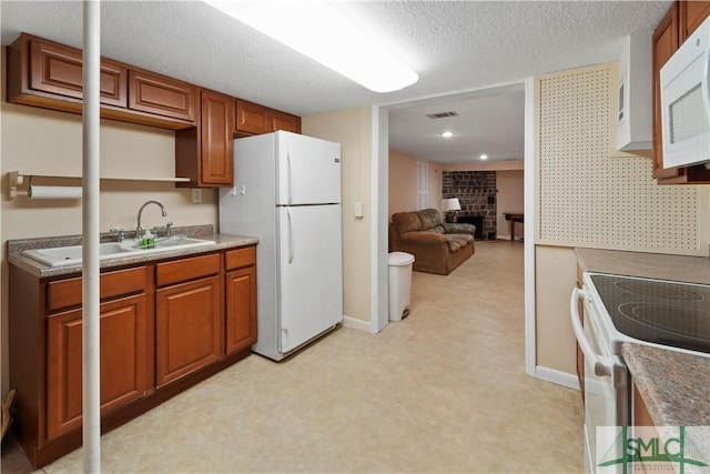 kitchen with visible vents, a brick fireplace, light floors, white appliances, and a sink