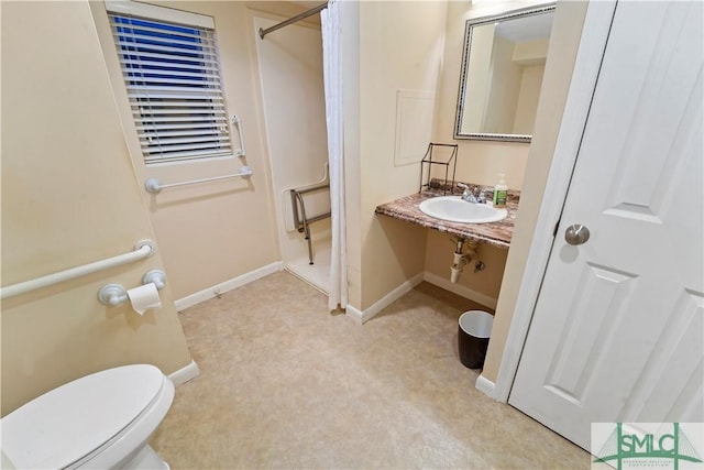 bathroom featuring a sink, baseboards, a shower, and toilet