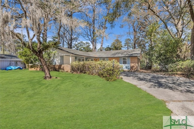 single story home featuring aphalt driveway, brick siding, and a front yard