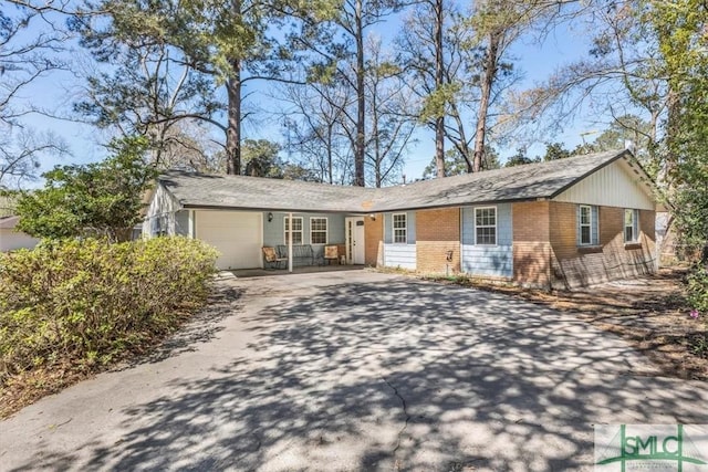 single story home featuring aphalt driveway, brick siding, and a garage