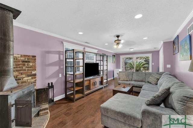 living area featuring a textured ceiling, wood finished floors, crown molding, ceiling fan, and a wood stove