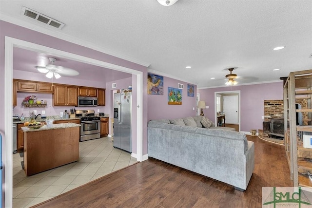 living area with visible vents, ceiling fan, and crown molding