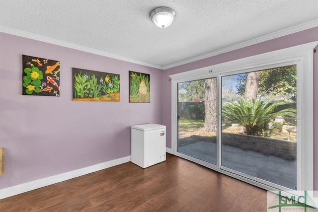 unfurnished room with a textured ceiling, baseboards, dark wood-style flooring, and ornamental molding