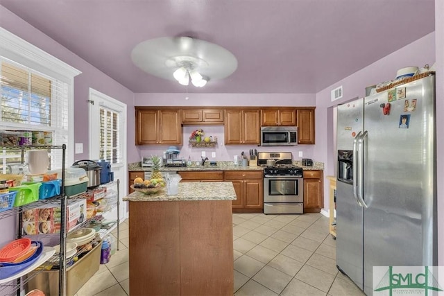 kitchen featuring ceiling fan, brown cabinets, light tile patterned flooring, stainless steel appliances, and a sink