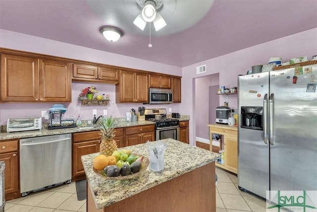 kitchen with light tile patterned floors, visible vents, ceiling fan, appliances with stainless steel finishes, and brown cabinets