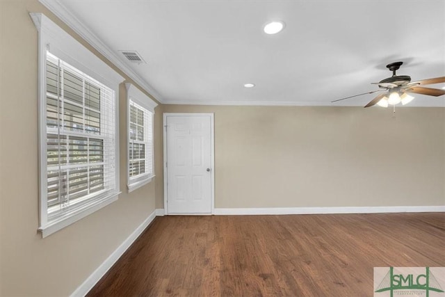 empty room featuring visible vents, ornamental molding, a ceiling fan, wood finished floors, and baseboards