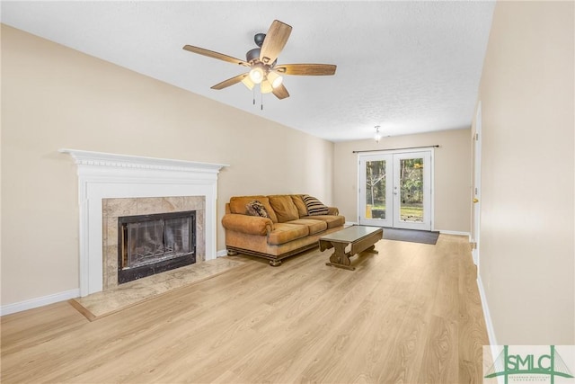 living room featuring light wood-style flooring, french doors, baseboards, and a premium fireplace