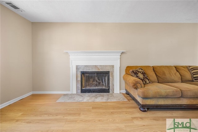 living area with wood finished floors, visible vents, baseboards, a fireplace, and a textured ceiling