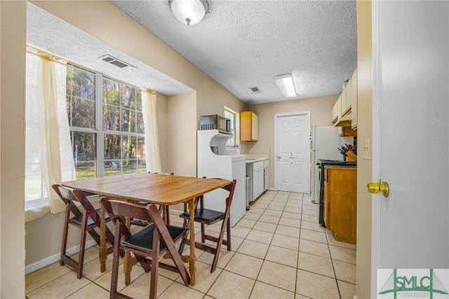 dining room featuring light tile patterned floors, baseboards, visible vents, and a textured ceiling