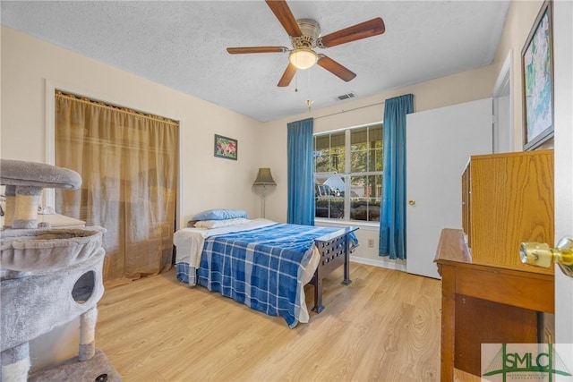 bedroom featuring visible vents, light wood-style floors, ceiling fan, and a textured ceiling