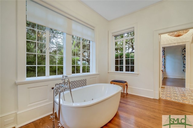 bathroom featuring a soaking tub, baseboards, and wood finished floors