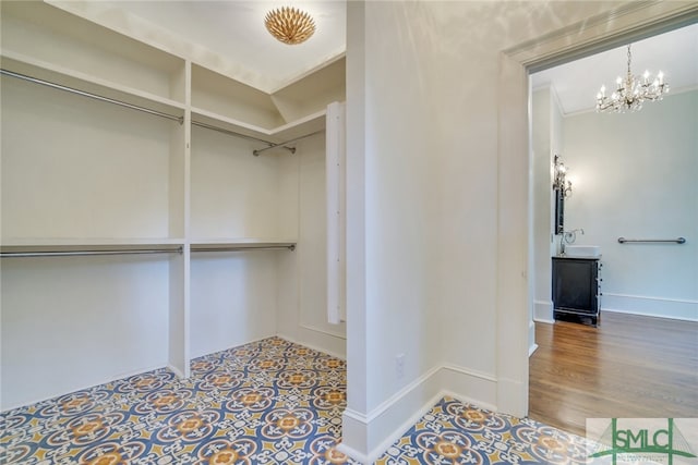 walk in closet featuring a sink, an inviting chandelier, and wood finished floors