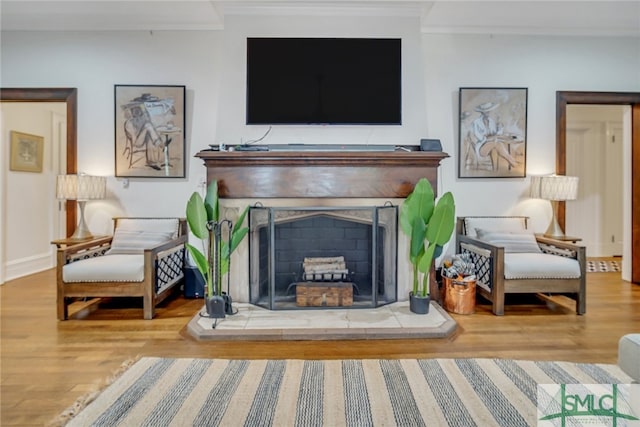 living room with ornamental molding, a fireplace, baseboards, and wood finished floors