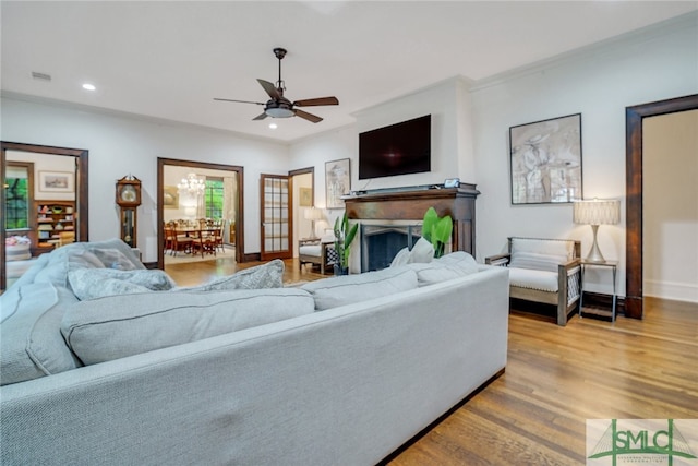 living area with visible vents, baseboards, recessed lighting, ceiling fan with notable chandelier, and wood finished floors