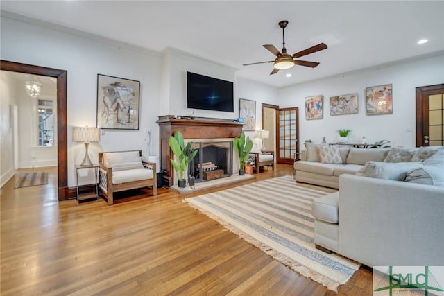 living area featuring recessed lighting, wood finished floors, a fireplace with raised hearth, and ceiling fan