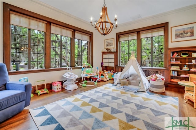 recreation room with plenty of natural light, an inviting chandelier, and crown molding