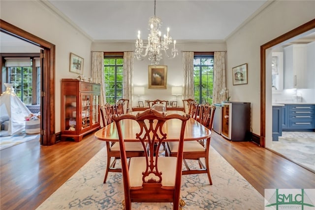 dining space featuring a wealth of natural light, wood finished floors, a notable chandelier, and ornamental molding