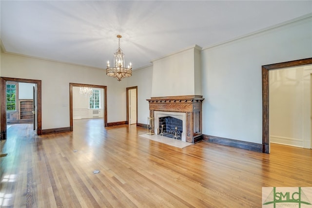 unfurnished living room featuring an inviting chandelier, a fireplace with flush hearth, light wood-type flooring, and plenty of natural light