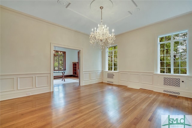 empty room featuring visible vents, an inviting chandelier, wood finished floors, and crown molding