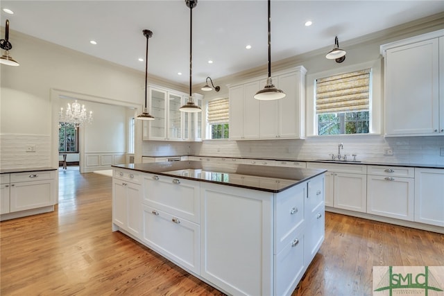 kitchen with dark countertops, plenty of natural light, a center island, and a sink