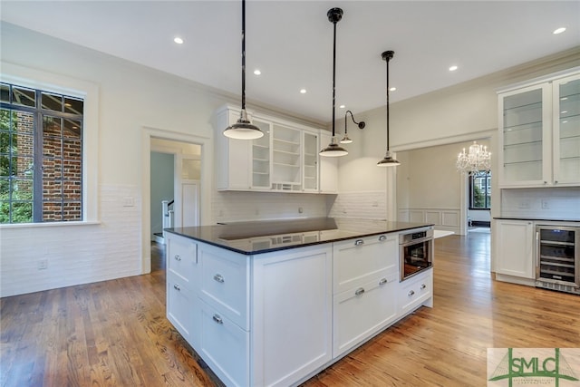 kitchen featuring dark countertops, beverage cooler, wainscoting, and white cabinets