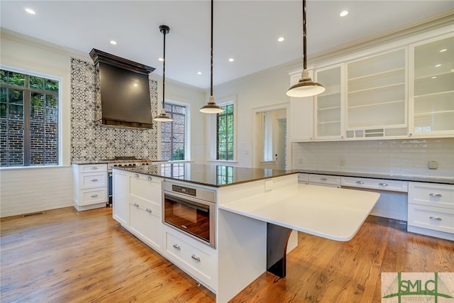 kitchen featuring dark countertops, light wood-style flooring, white cabinetry, and glass insert cabinets