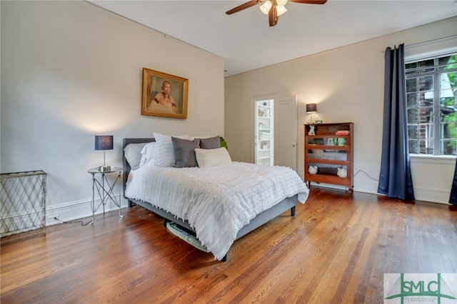 bedroom featuring baseboards, wood finished floors, and a ceiling fan